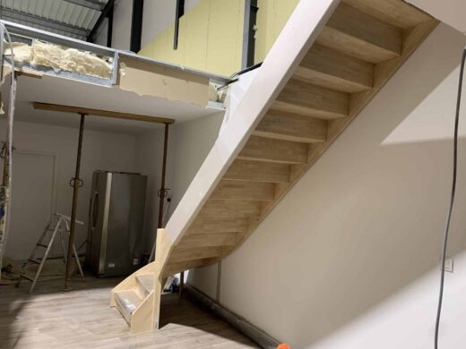 Un escalier en bois mène à un loft.
