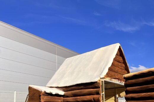 Cabane en rondins avec toit blanc, échelles autour.