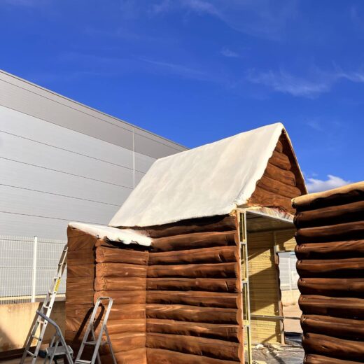 Cabane en rondins avec toit blanc, échelles autour.