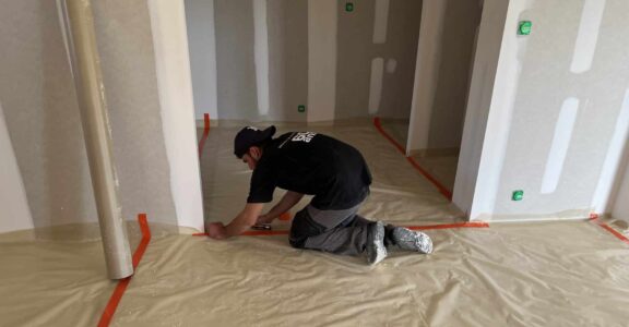 En tenue de travail, coller du plastique au mur.