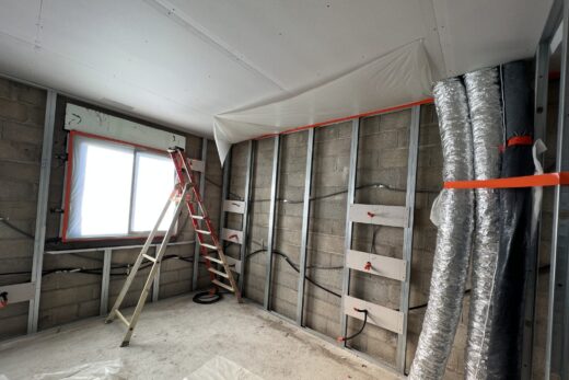 Pièce en construction : murs ouverts, échelle, conduits visibles.