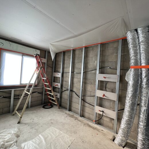 Pièce en construction : murs ouverts, échelle, conduits visibles.