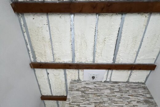 Inachevé : plafond isolé, mur pierre, porte visible.