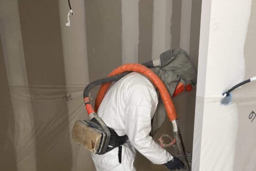Personne en équipement pulvérisée dans une pièce inachevée.