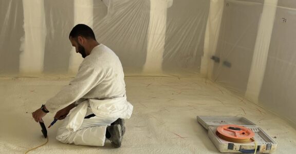 Personne agenouillée, travaux d'isolation des sols.