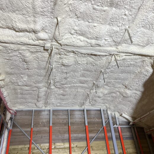 Plafond avec mousse isolante, tuyaux visibles.