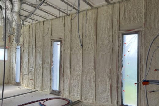 Pièce en construction avec isolant exposé et câbles.