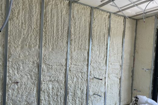 Mur avec montants métalliques, mousse pulvérisée, fils saillants.