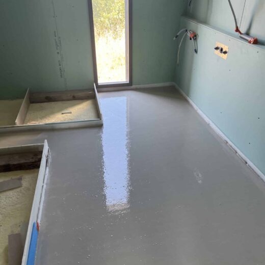 Pièce en construction avec sol en béton et lumière du soleil.