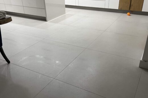 Sol de cuisine avec grand carrelage, boule dans coin.