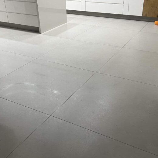 Sol de cuisine avec grand carrelage, boule dans coin.